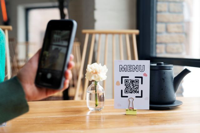 カフェのテーブルのQRコードのPOPをスマホのカメラで読み取るイメージ