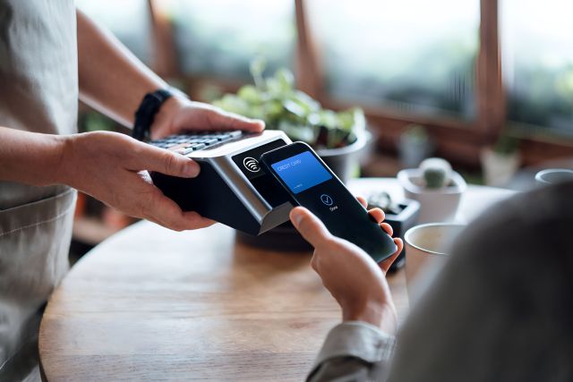 スマホのタッチ決済を利用する顧客とキャッシュレス決済端末で対応する店員