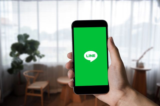 右手でLINEアプリのアイコンが表示されたスマホを持つイメージ