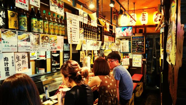 居酒屋のカウンター席にいる複数の来店客