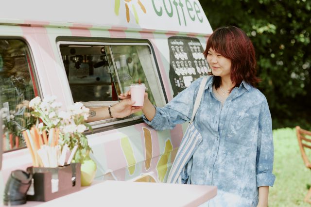 キッチンカーでドリンクを購入する女性のイメージ
