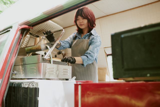 キッチンカーの車内で調理をする女性