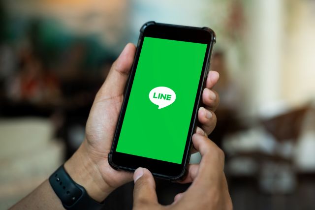 LINEのアプリ画面が表示されたスマホを手に持つイメージ