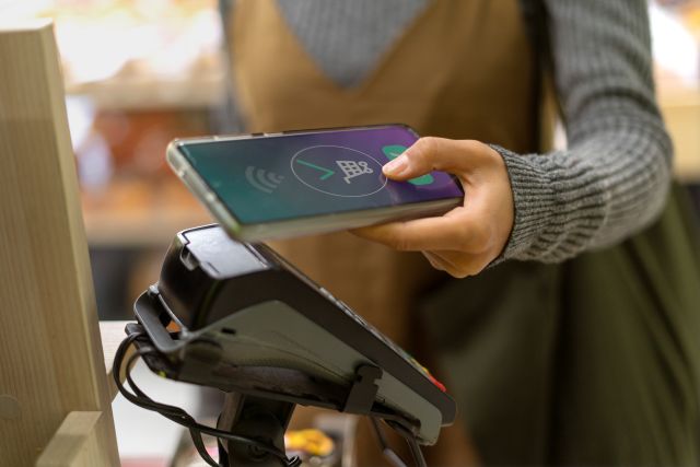 決済端末にスマホをかざしてタッチ決済する顧客のイメージ