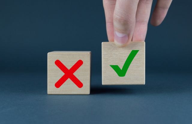 ×印とチェック印が描かれた木製ブロックのうち、チェックブロックをつまむイメージ