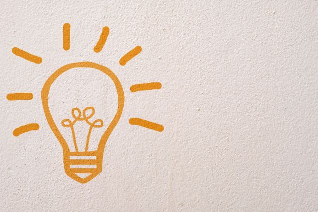コンクリート壁に描かれたオレンジ色の電球
