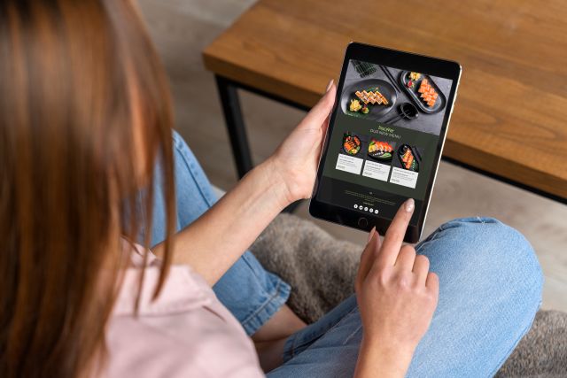 タブレット端末で料理のオーダー画面を見る女性