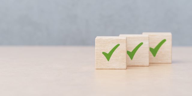 テーブルの上にチェックマークのついた木製キューブが3つ並ぶイメージ