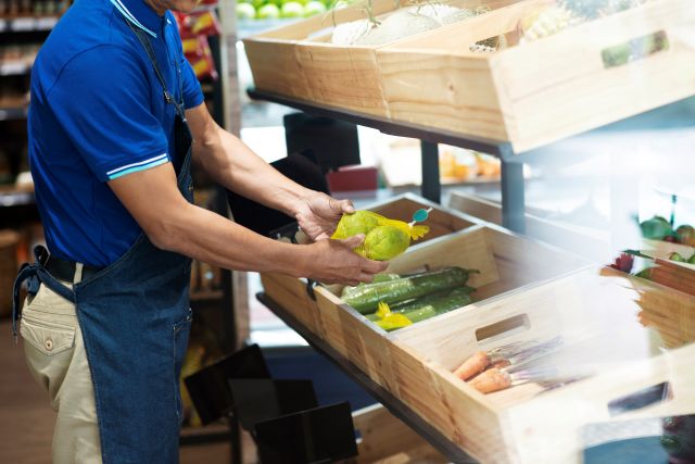 直売所の野菜売り場に商品を並べるスタッフのイメージ