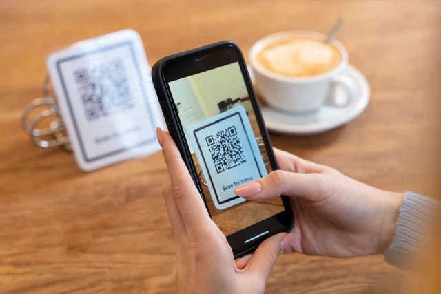 カフェでテーブル上のQRコードをスマホでスキャンするイメージ