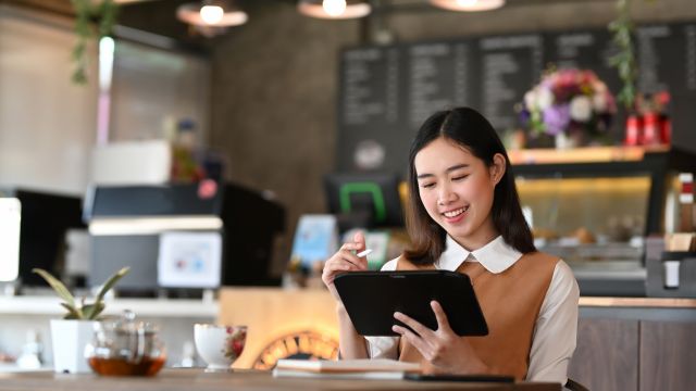 カフェでタブレット端末を操作する女性