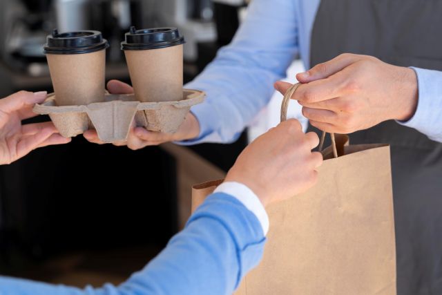 カフェで持ち帰りの商品を受け取る人の手元