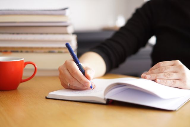 テーブルに書籍を積んで勉強している人のイメージ