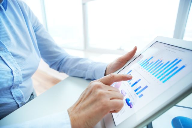 タブレット端末で棒グラフなどのデータを確認する人のイメージ