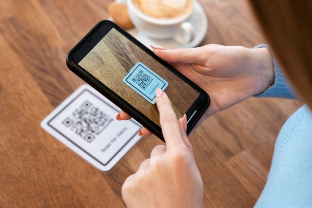 テーブル上のQRコードをスマホで読み取る女性