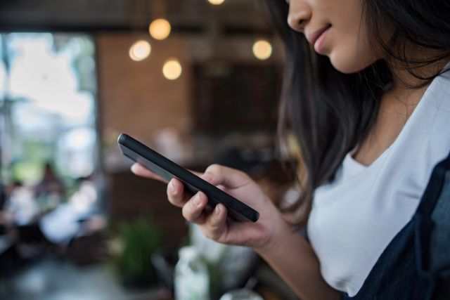 飲食店の店内でスマホを操作する女性