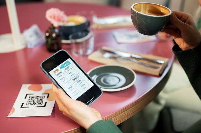 飲食店のテーブルに置かれたQRコードとメニューを表示させたスマホ