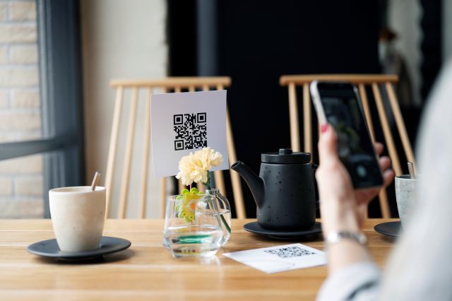 カフェのテーブルでQRコードをスマホで読み取るイメージ