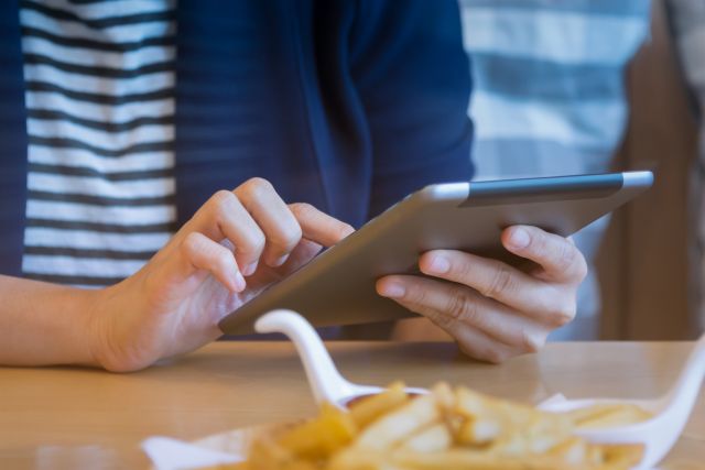 飲食店のテーブルでタブレットを操作する人のイメージ