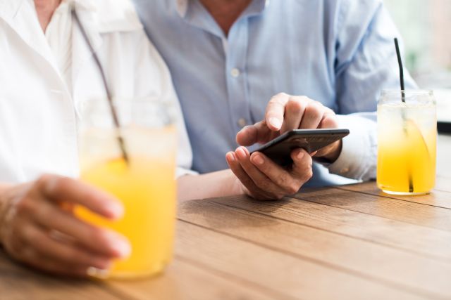 テラス席でドリンク片手にスマホを操作する2人組
