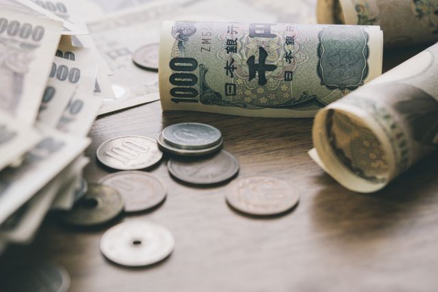 テーブルに日本の紙幣と硬貨が散らばっているイメージ