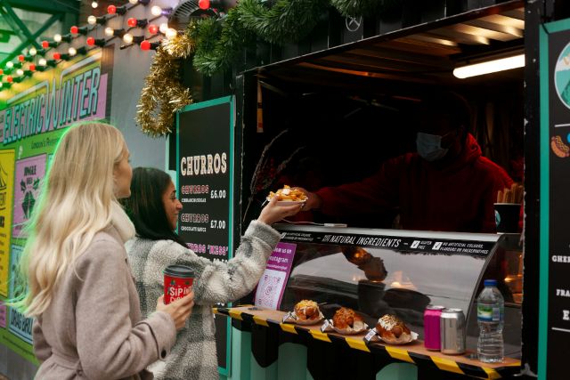 キッチンカーで飲み物を買う女性