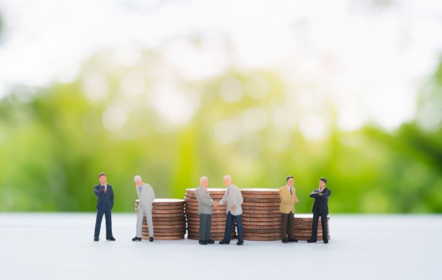 ミニチュアのビジネスマンとコインのスタック