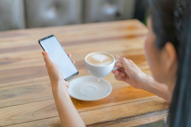 カップとスマホを持つ人
