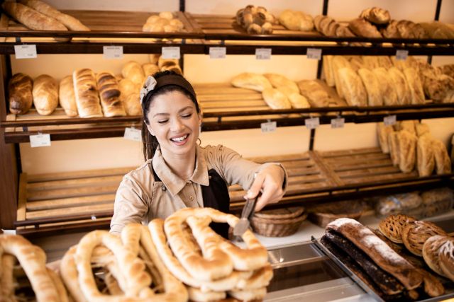 ベーカリーショップで顧客に焼きたてのペストリーを販売する女性