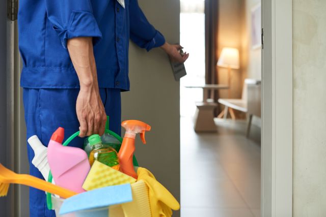 清掃用具を持った人が部屋に入室するイメージ