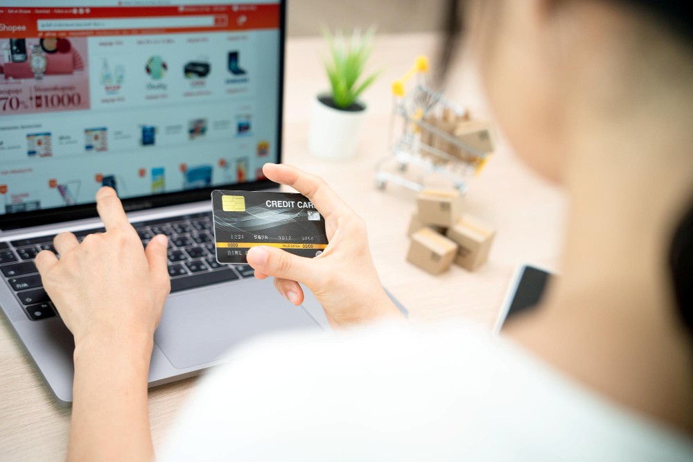 パソコンを見ながらクレジットカードで決済しようとする人