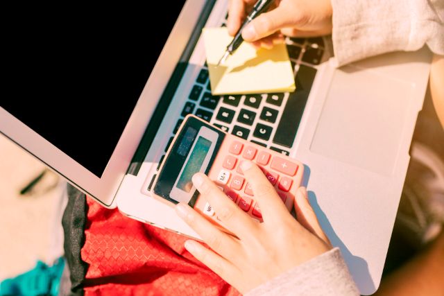 クレジットカードを見ながら電卓を叩く手