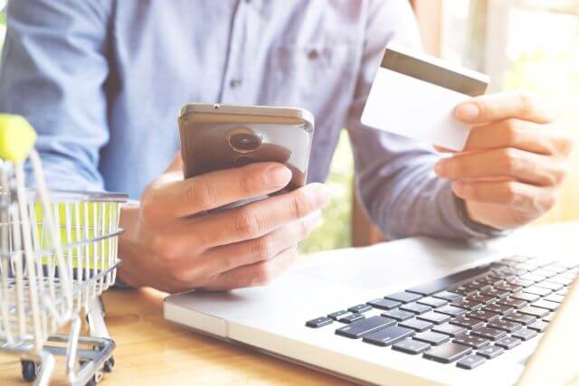 クレジットカードを見ながらスマホを持つ男性