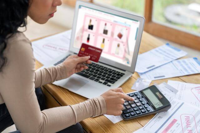 クレジットカードを見ながら電卓を叩く女性